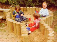 Песочница с бортиками из поленьев является отличной идеей при оформлении детской площадки. Источник http://www.pro-landshaft.ru